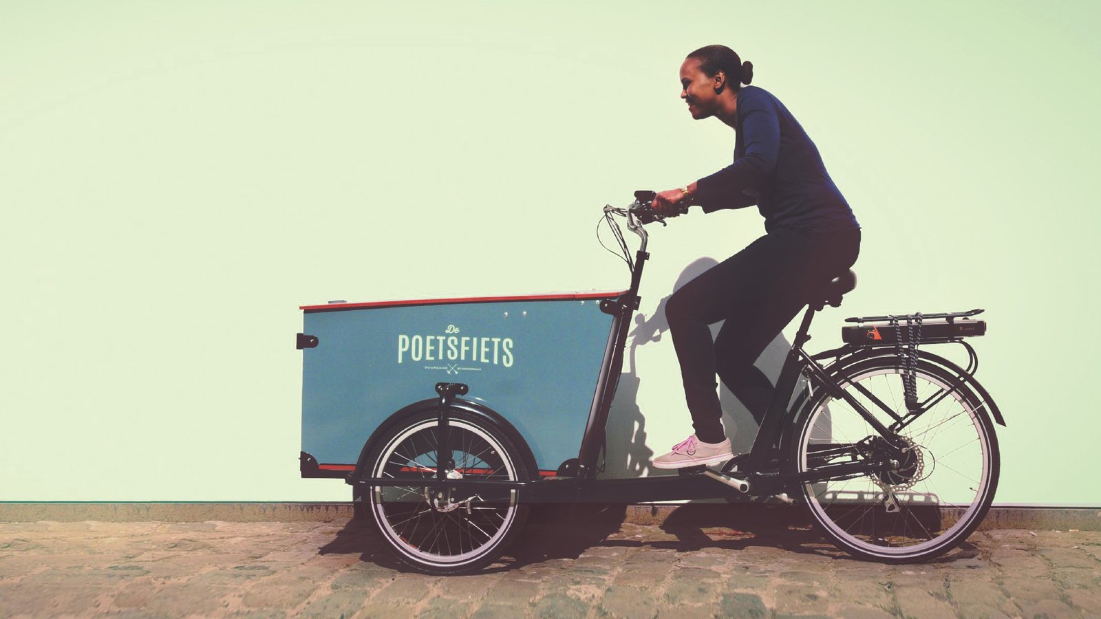 Poetsfiets met bak en een fietser voor een lichte muur